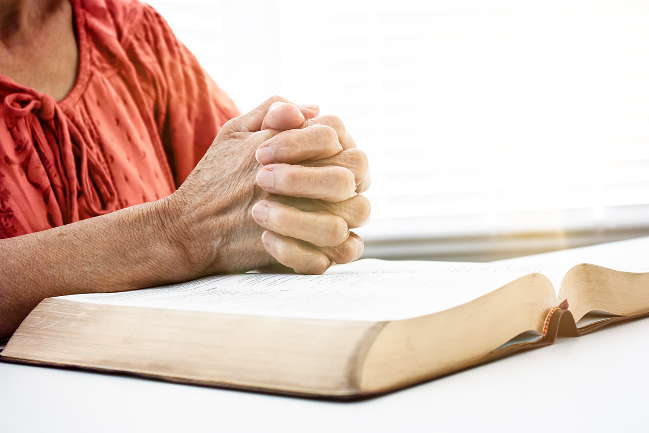Una Biblia con una persona rezando